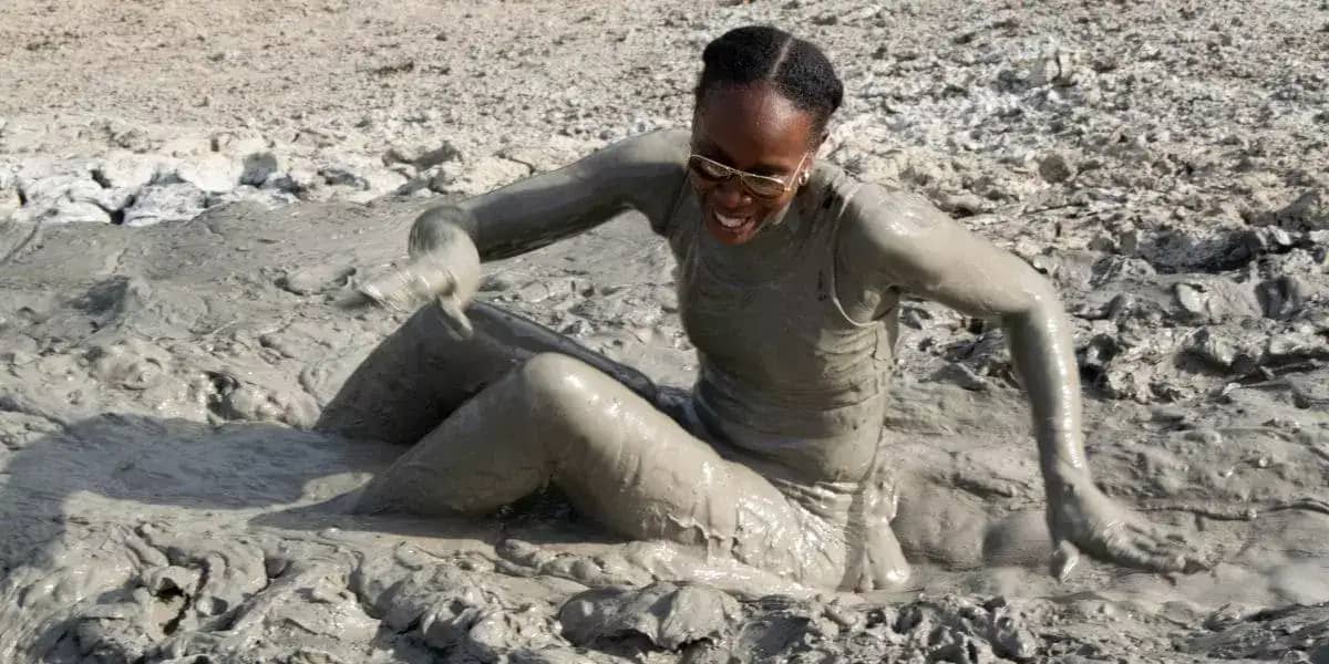 a lady playing in the mud after skating down a volcanic mud slope